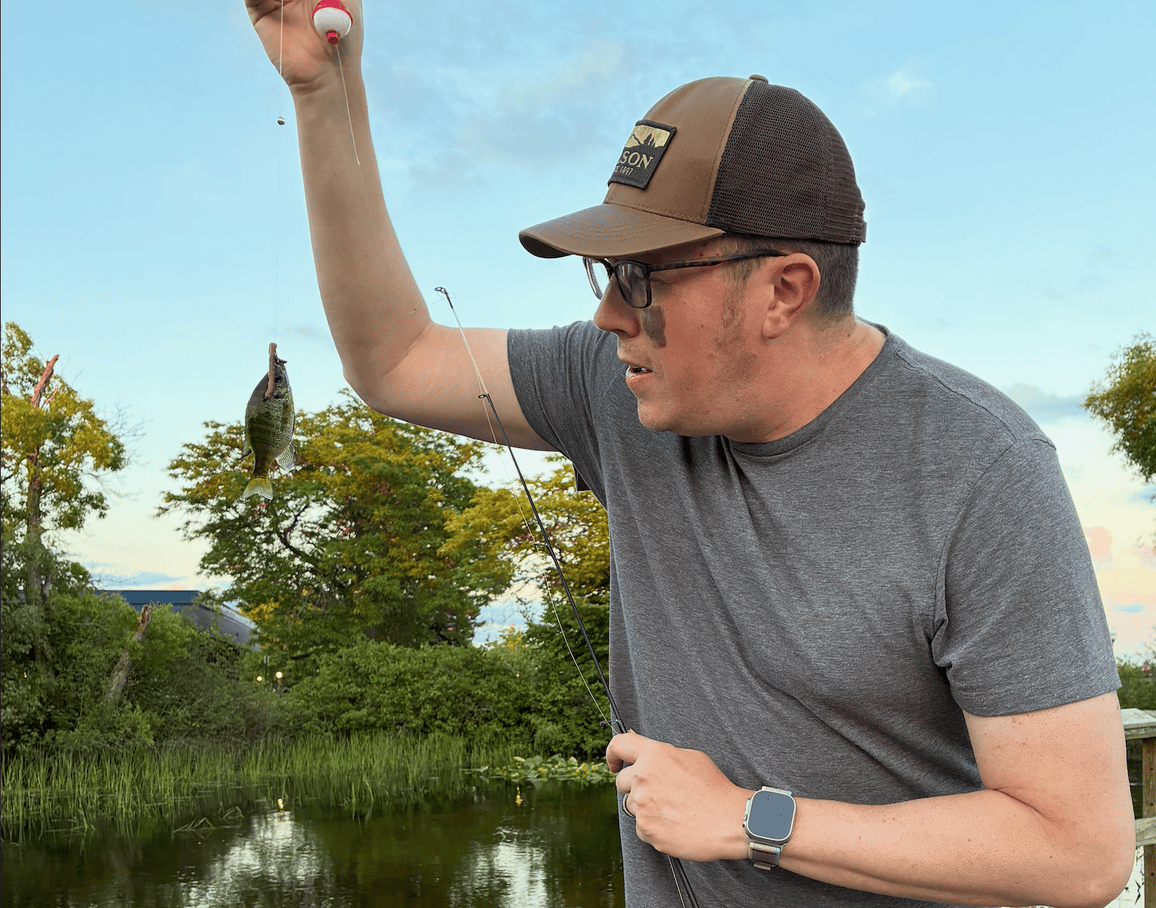 Pete McPherson lifting a small panfish off a bobber rig at the shoreline at dusk